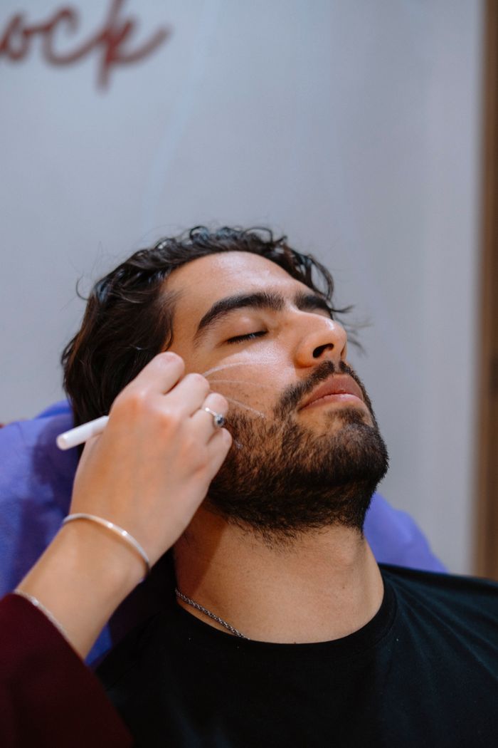 Offerings Man receiving grooming treatment in a modern barbershop, relaxed setting with attention to detail.
